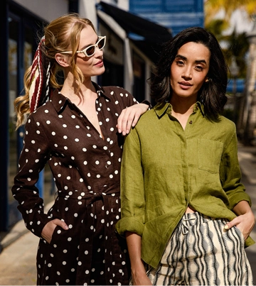 Model trägt ein weißes Leinenhemd und eine beige Leinenhose, sitzt auf einem Stuhl und blickt nach rechts