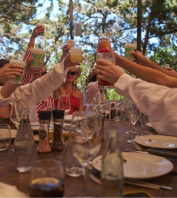 Gruppe von Freunden, die im Sommer gemeinsam am Tisch ihre Gläser hebt