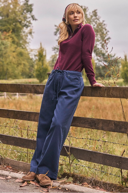 Frau trägt einen bordeauxfarbenen Pullover und Jeans mit weitem Bein im Freien